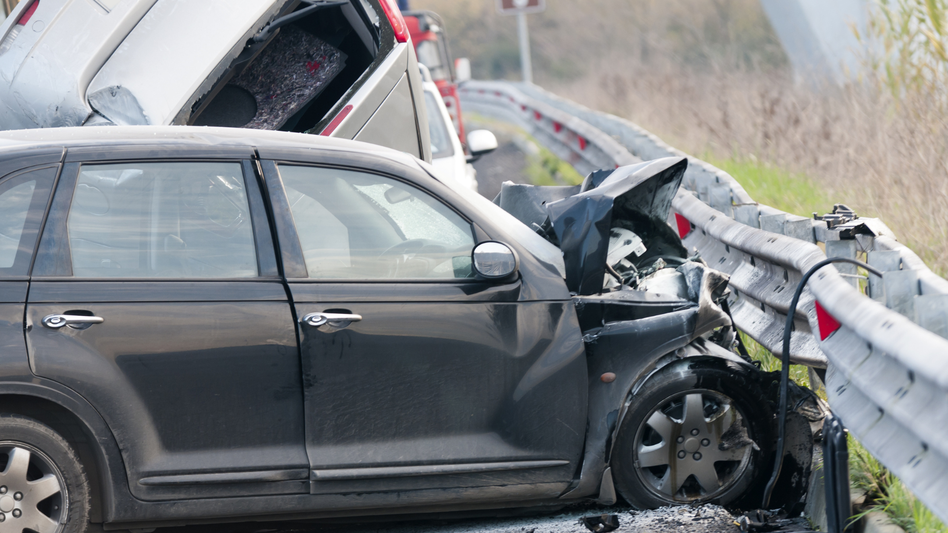 Severe car crash on a highway with a vehicle smashed into a guardrail and another overturned, illustrating serious Seattle car accidents.
