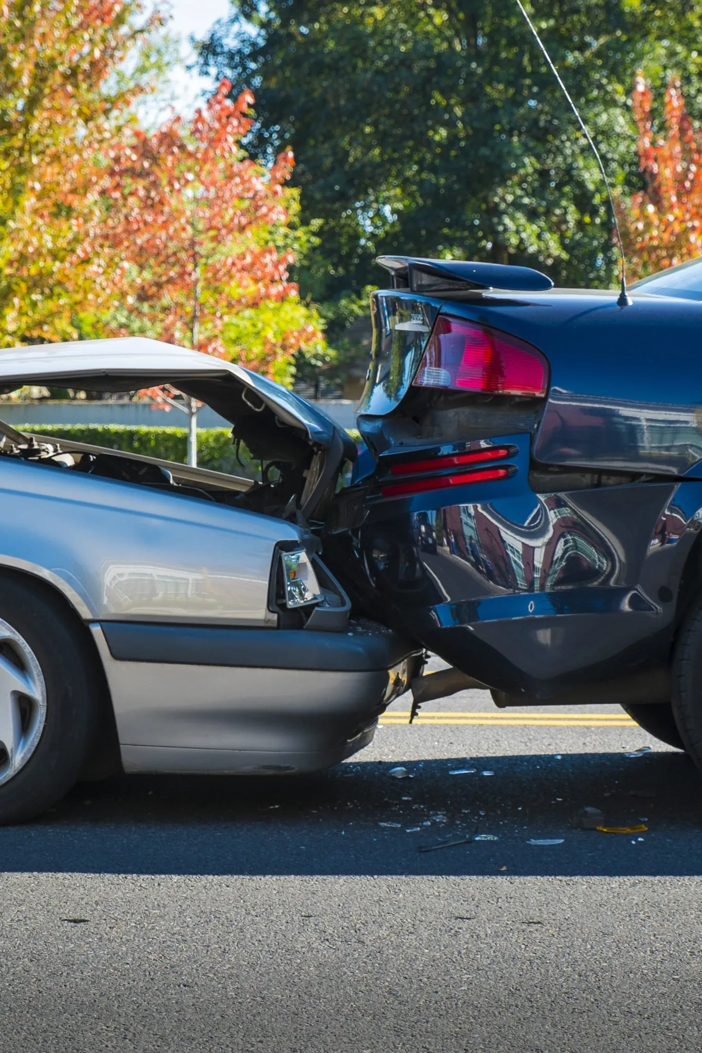 Two cars involved in a rear-end collision on a sunny Seattle street, showing visible bumper and trunk damage.
